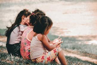 Children sitting on a bench together.